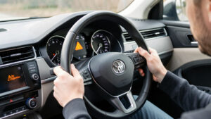Tableau de bord réaliste d’une voiture moderne, voyant d’injection allumé, conducteur attentif dans l’habitacle, ambiance technique et éclairage naturel.