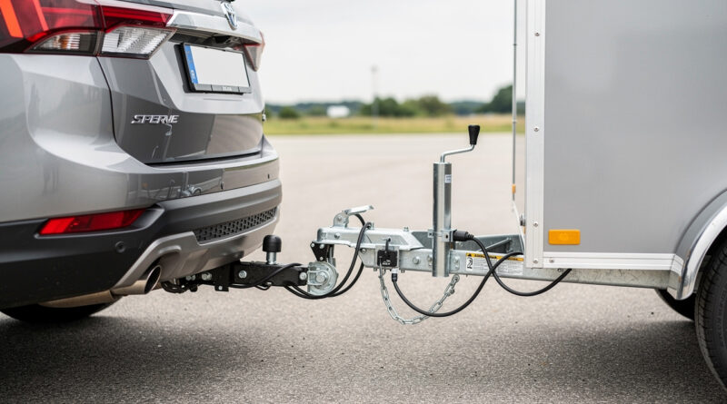 Vue arrière réaliste d’un véhicule muni d’un attelage col de cygne relié à une petite remorque bagagère, avec le raccordement électrique visible sous une lumière naturelle.
